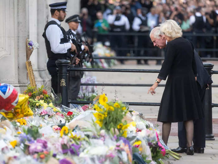 King Charles III and Queen Consort Camilla stopped to look at flowers left by the public at Buckingham Palace in their first public appearance following the Queen