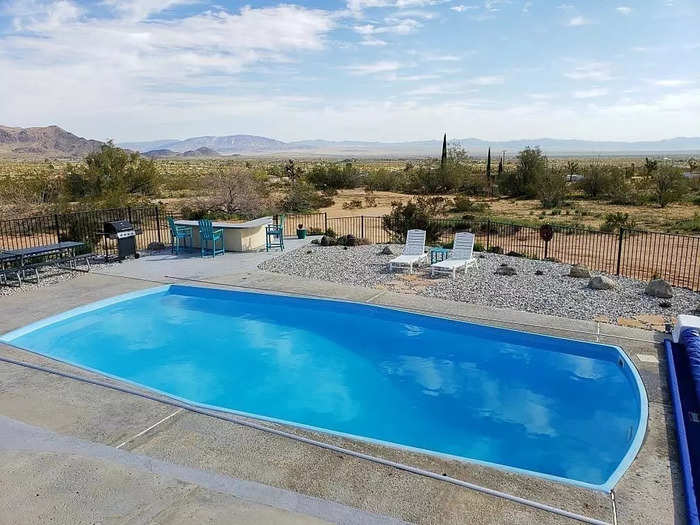 The backyard includes the pool, a hot tub, seating areas, and a barbecue. Monroe added new Adirondack chairs, an automatic pool cover, a fire pit, and a shade pergola to the outdoor space.