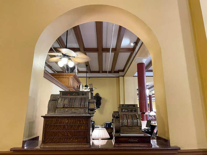 In one hallway, a bust of the founder was placed on a marble pillar, a piano was stationed against a wall, and antique cash registers sat on a shelf.