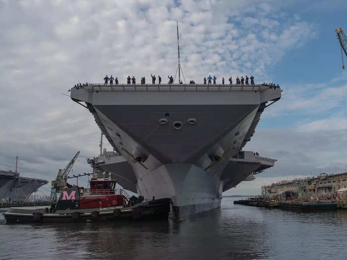 A tugboat directs the Ford-class aircraft carrier USS Gerald R. Ford as it leaves the pier in Newport News, Virginia, October 25, 2019.