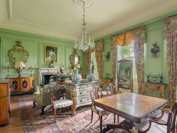 The second reception room has a light and airy feel to it, with mint-green walls, a dining table, cabinets, and a fireplace.