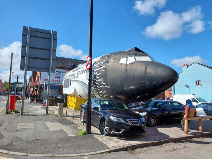 This is the restaurant as you approach from the sidewalk. The plane is surrounded by cars, presumably owned by staff and diners, and the restaurant