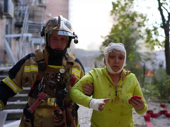 A rescuer helps an injured woman at a site of a damaged building in Kyiv.