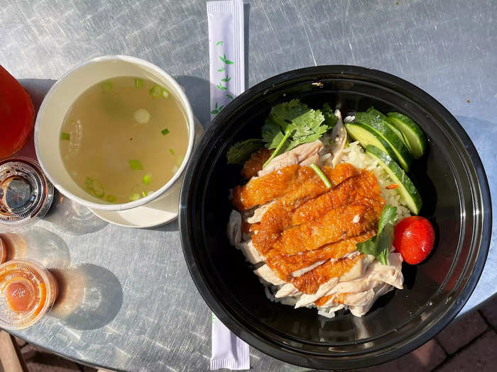 The dish came with a serving of chicken that had been poached and then roasted with an oil baste, as well as rice cooked with garlic, shallots, stock, and pandan. It was served with raw cucumber slices, a cherry tomato, a bowl of soup, and two dipping sauces.