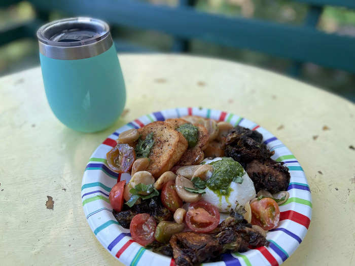 I dug into (now room temperature) roasted Brussels sprouts and a small plate of burrata, heirloom tomatoes, roasted garlic, fresh basil pesto, and toasted crostini. A metal tumbler of red wine I