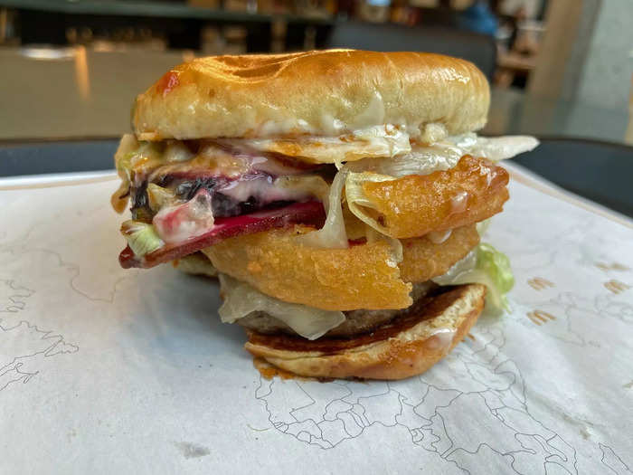 It includes 100% Aussie beef, garlic mayo, shredded lettuce, a beet root slice, onion rings, Monterey jack cheese, and rasher of bacon on an artisan roll.