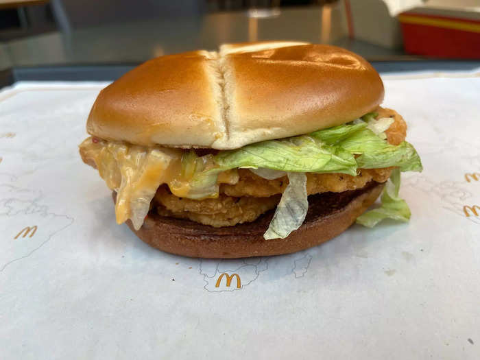 The sandwich includes two crispy McChicken patties, shredded lettuce, and Kung Pao dressing on a cross bun.