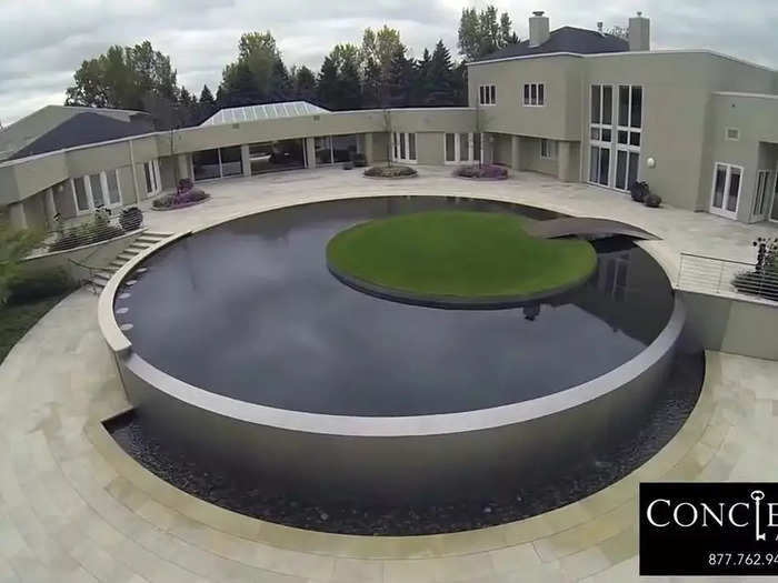 The back patio boasts a round infinity pool punctuated by a patch of grass in the middle.