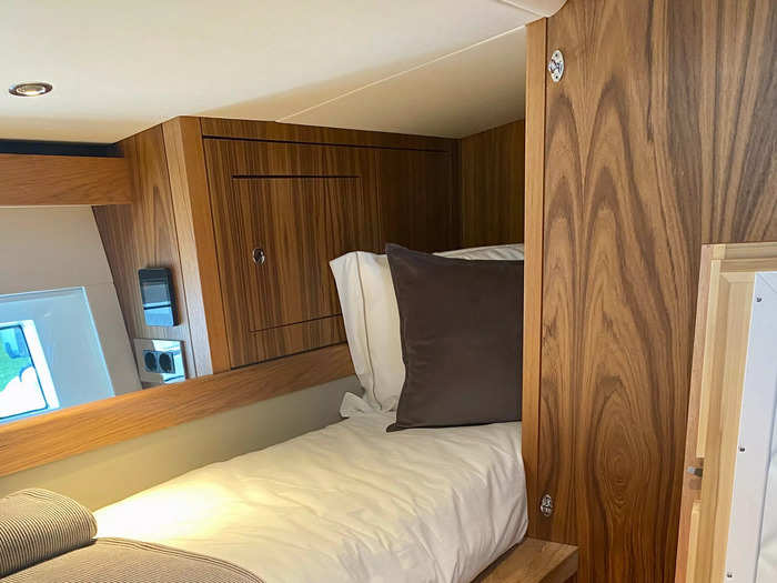 The bed was extremely narrow and sat on top of storage cupboards. There was a small porthole window next to the bed that looked out onto the sea.