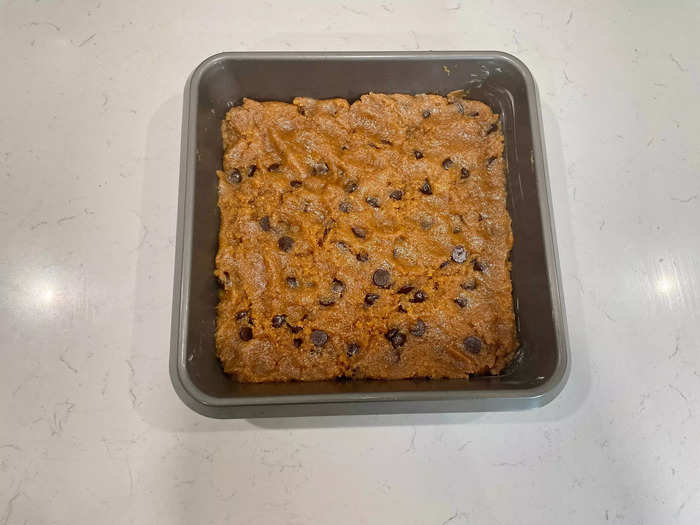 Spread the cookie dough along the bottom of the baking pan to form the first layer of the slutty brownies.