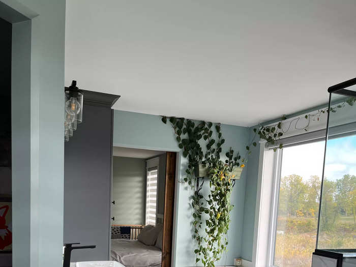 The en suite bathroom has a marble-counter sink and hanging plants for a relaxing feel.