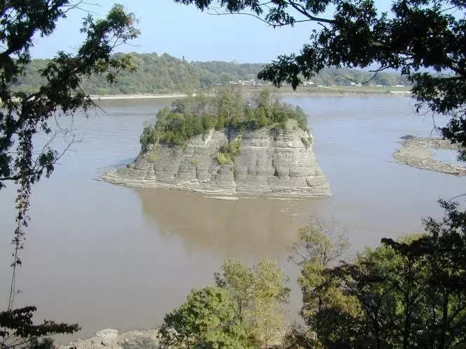 big rock formation island topped with trees sits in mississippi river