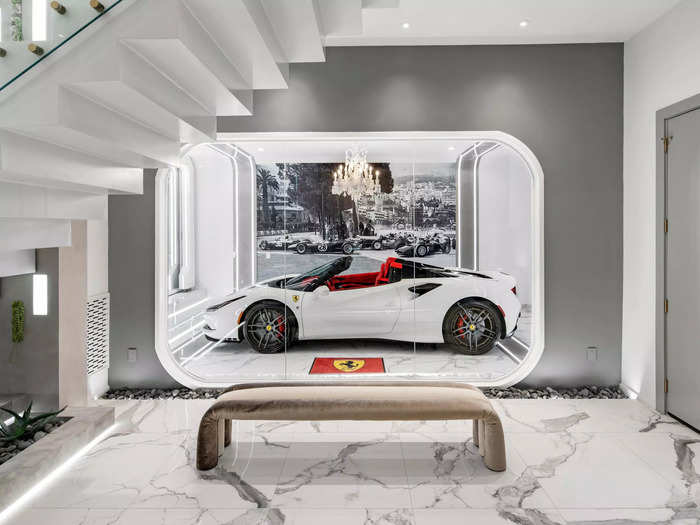 The living room features a two-story porcelain fireplace and a glass-walled car showroom that houses Jackson