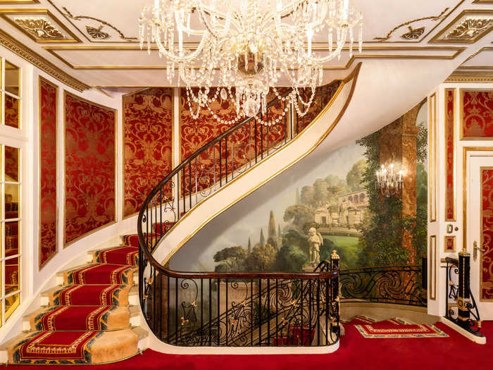 The home includes a dramatic winding staircase with a dark metal handrail contrasted with bright red wallpaper and carpet.