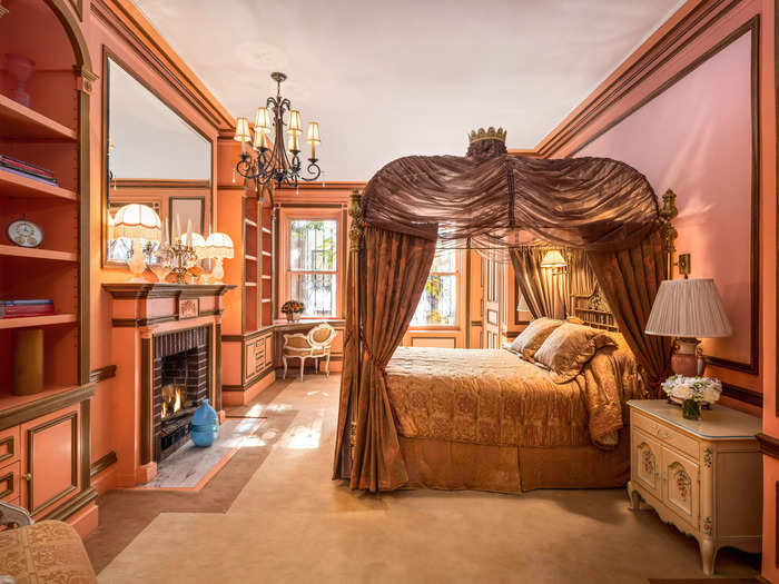 One of the bedrooms includes a canopy bed and a salmon-colored aesthetic.