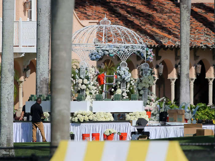 Event staff decorated an outdoor gazebo with light blue and white flowers as part of wedding preparations.