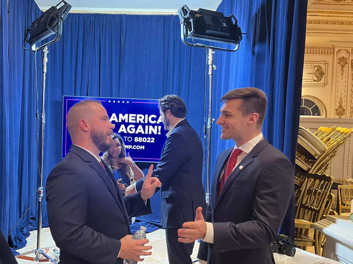 Guests Graham Allen (left) speaks to Alex Bruesewitz, Co-Founder and CEO of X Strategies near the MAGA video booth.