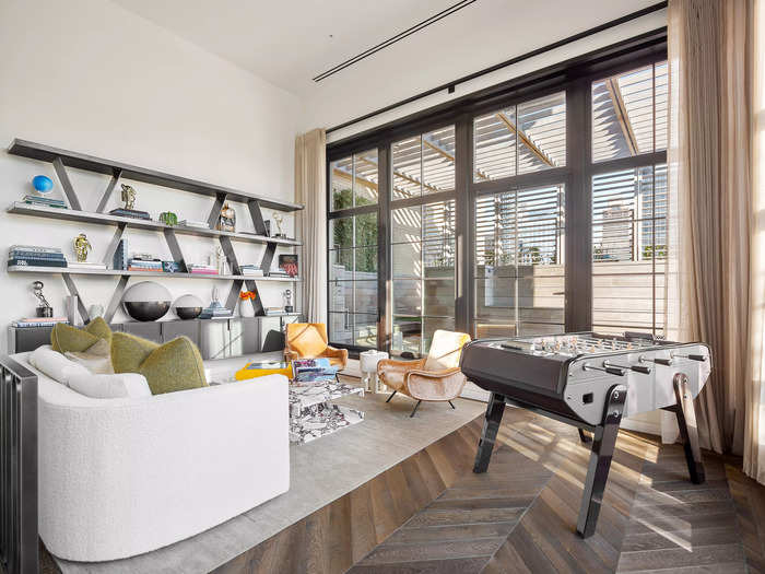 The walls of the living space are covered in various textures, such as Jerry Pai suede leather and Kamp Studios hand plastering, to create a warm atmosphere. A Grigio Carnico marble fireplace and a cast-iron ladder leading to a lofted office give the space an elevated feeling.