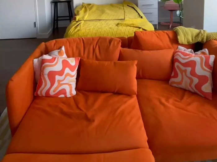 Lauren incorporates a bold color into her space with her orange couch and throw pillows.