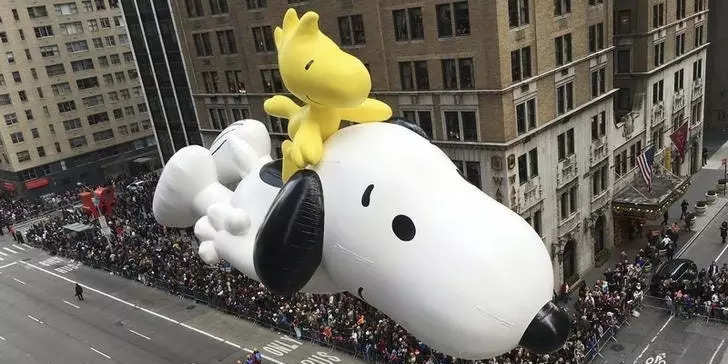 A float depicting the animated "Peanuts" characters Snoopy and Woodstock proceeds along 6th Ave as spectators watch from buildings during the 89th Macy