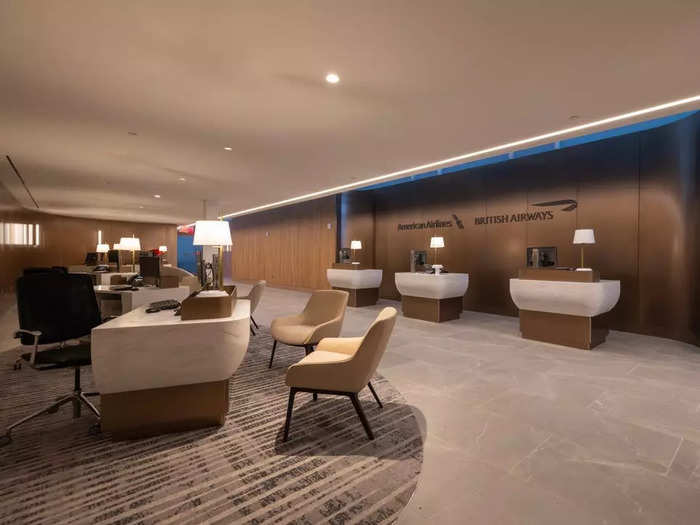 The first check-in area is a private room that features desks, marble ascents, and couches. The exclusive space is hidden away behind glass doors.