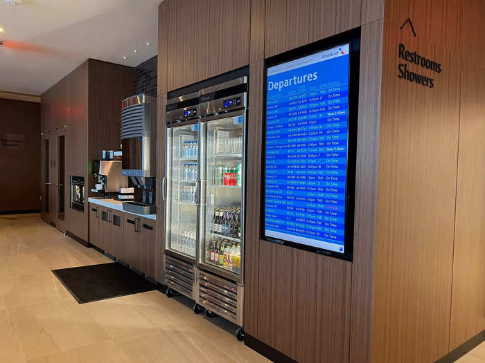 Just beyond the dining area on the right side of the lounge is a refrigerator full of drinks, like water, soda, and beer, as well as a coffee station…