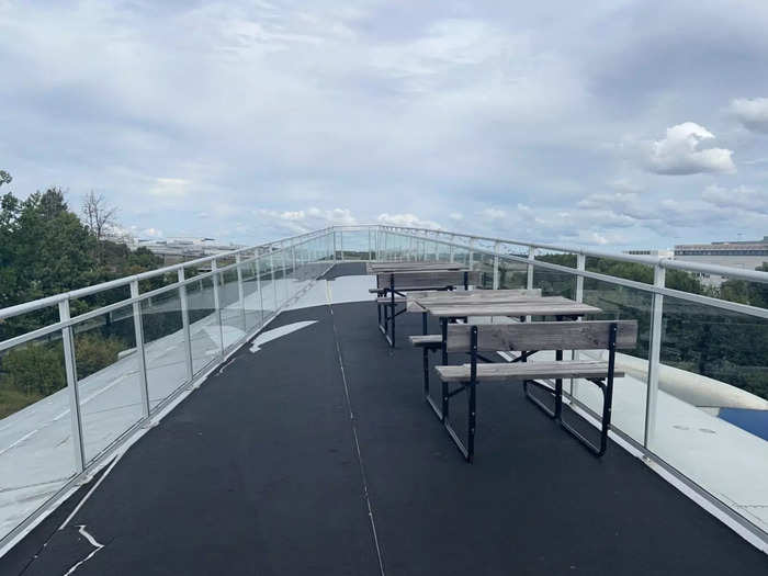 The wing is set up as a social space with tables and chairs. It overlooks part of the airport so it