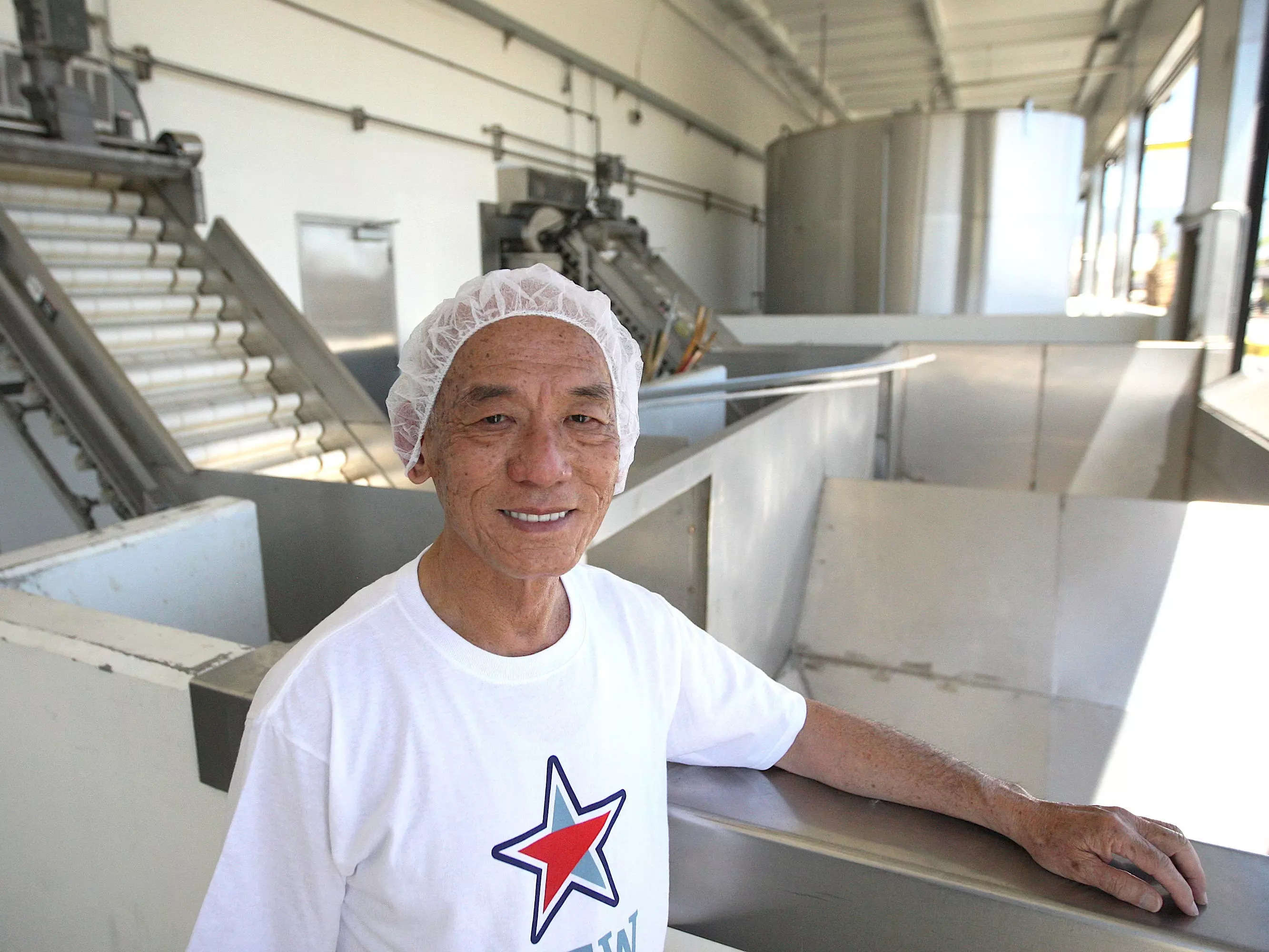 Huy Fong Foods CEO David Tran poses next to hoppers where chilies are delivered during chili crushing season at the Sriracha Hot Chili Sauce factory on May 14, 2014 in Irwindale, California.