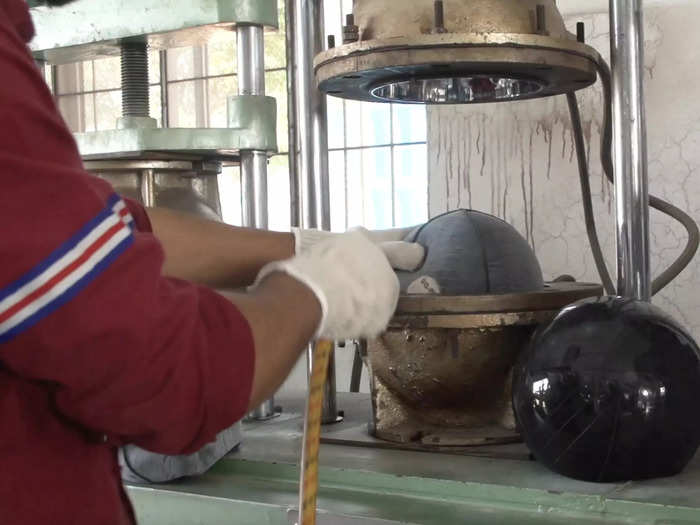 Then the worker places the lining into a metal steam machine, where it bakes for a few minutes, hardening the rubber.