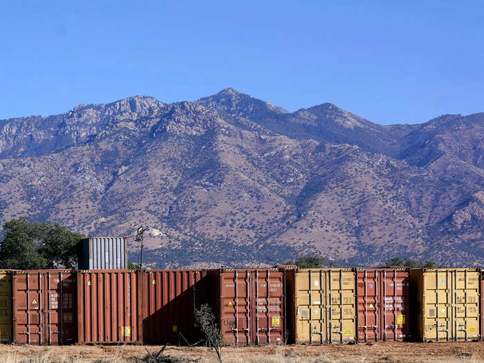 A long row of shipping containers wait for installation along the border where hundreds shipping containers create a wall between the United States and Mexico in San Rafael Valley, Ariz., Thursday, Dec. 8, 2022.