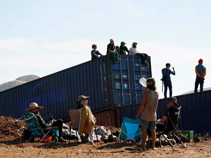 Activists gather near and sit on newly installed shipping containers along the border creating a wall between the United States and Mexico in San Rafael Valley, Ariz., Thursday, Dec. 8, 2022.