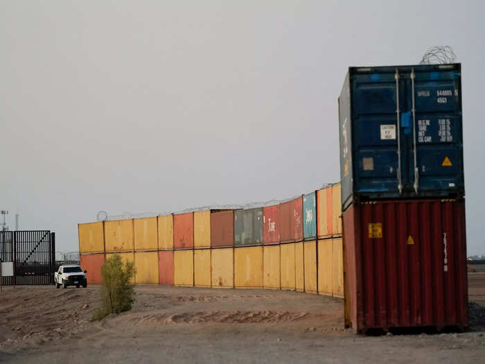 Border Patrol agents patrol along a line of shipping containers stacked near the border Tuesday, Aug. 23, 2022, near Yuma, Ariz.