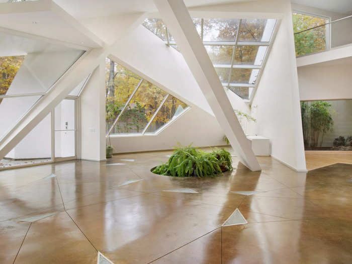 Artfully placed windows in the foyer let in sunlight and views of the surrounding trees. Angled support beams emphasize the home