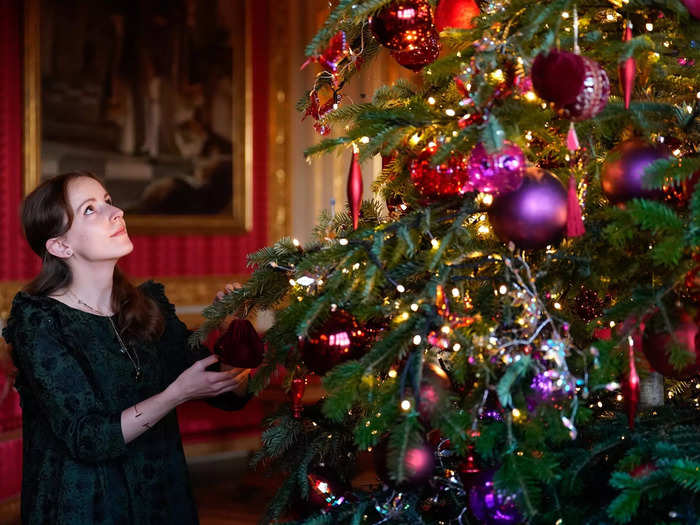 The tree is adorned with red, gold, and purple ornaments in honor of Queen Elizabeth II.