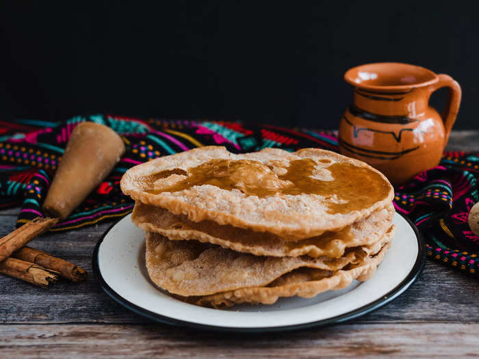 Traditional Mexican-style buñuelos are thinly fried dough dusted with sugar, cinnamon, and drizzled with caramel.