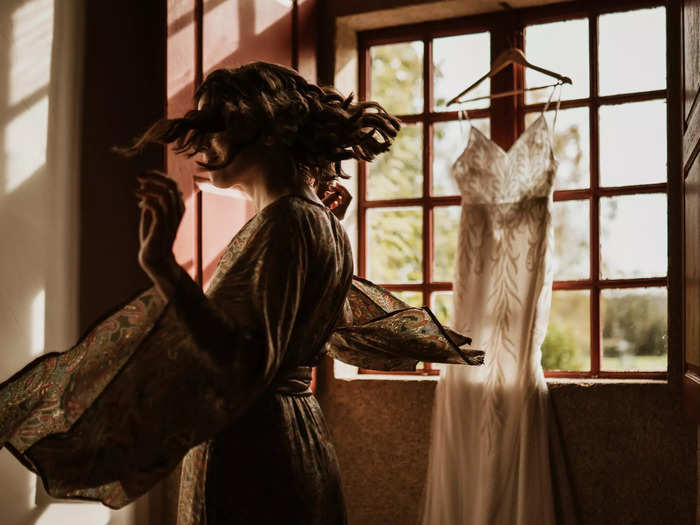 A photographer caught a bride dancing with excitement in front of her dress.