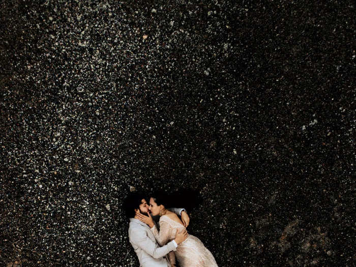 An aerial shot showcases the newlyweds at a breathtaking black-sand beach.