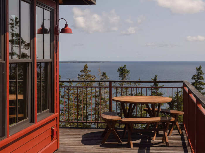 A 360-degree outdoor deck surrounds the home, offering a scenic view of the nearby forest and the Atlantic ocean.