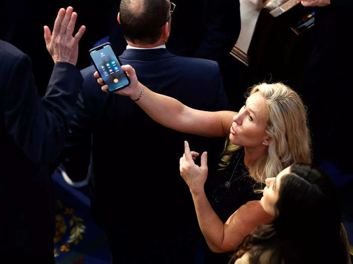 Marjorie Taylor Greene holds a phone out to Representative-elect Matt Rosendale during the 14th voting session.