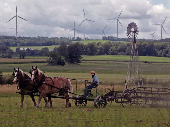 Changes to the land around Amish communities continued to become more stark. Here, a farmer works his land, while wind turbines spin in the distance.