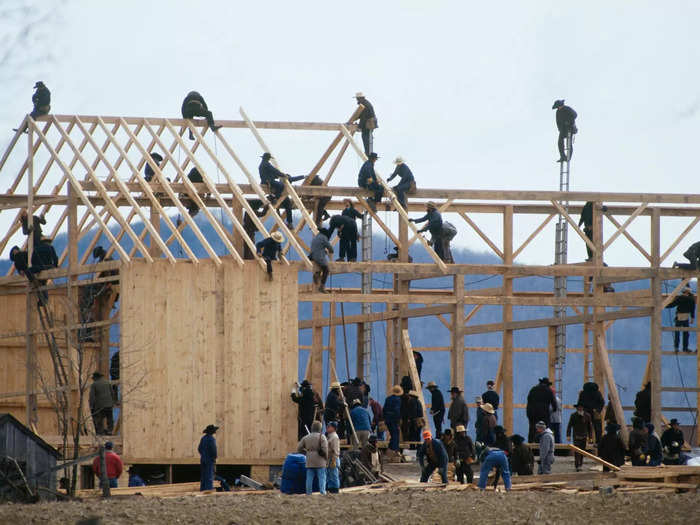 They work together. Here, men rebuild a barn that was destroyed by arson in 1992.