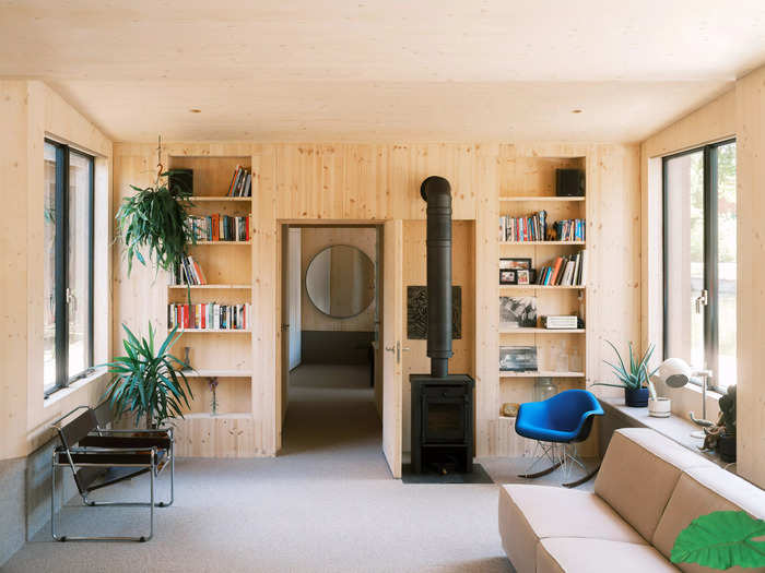 The rooms of the floating house are arranged in a row, centered around the living room. The kitchen and dining area are on one end, while the bedroom is on the opposite side.