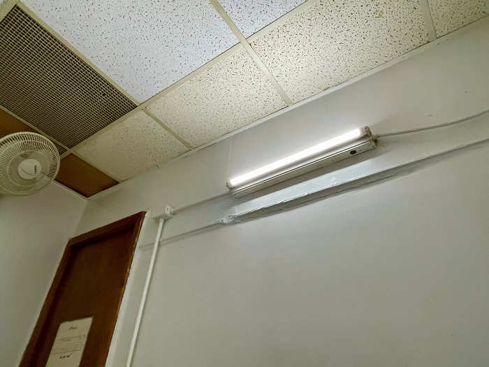 A fan hung from the ceiling near the door, and there was a strip light on the wall.