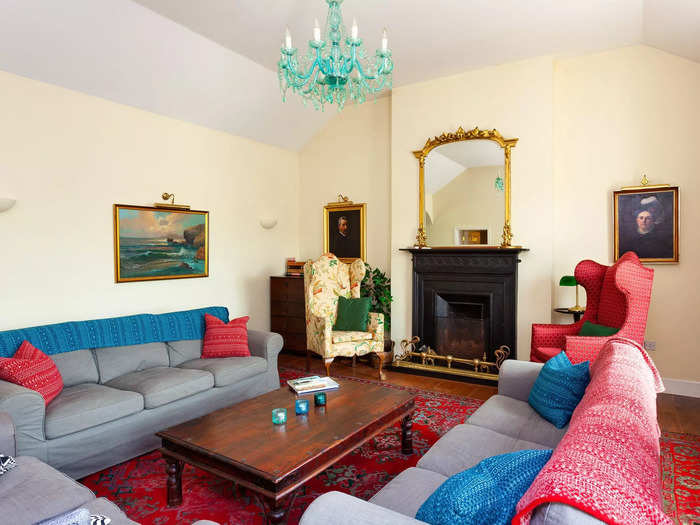 The sitting room has a fireplace, chandelier, and cozy furniture.