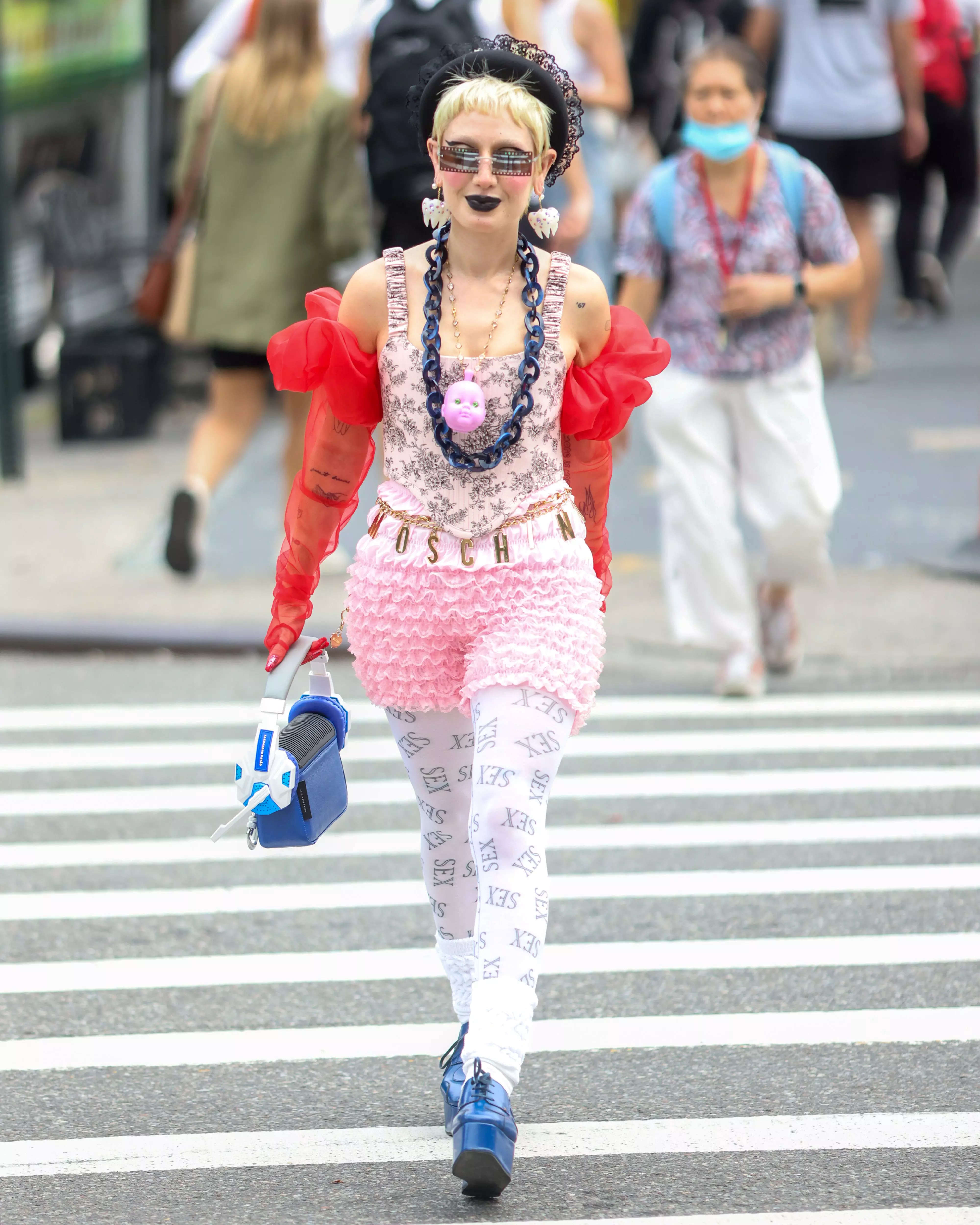 Stylist Sara Camposarcone walks down the street in a pink and red outfit with blue shoes