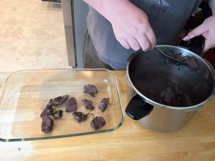 Use a slotted spoon to transfer the meat from your pot to a baking dish, and spread the meat evenly.