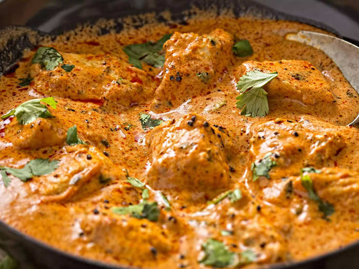 Dip naan bread into butter chicken, a classic Indian meal with spices and a creamy tomato sauce.