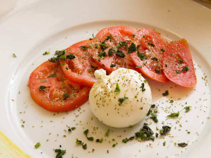 Eat Italian caprese salad with tomatoes, basil, and fresh mozzarella cheese.