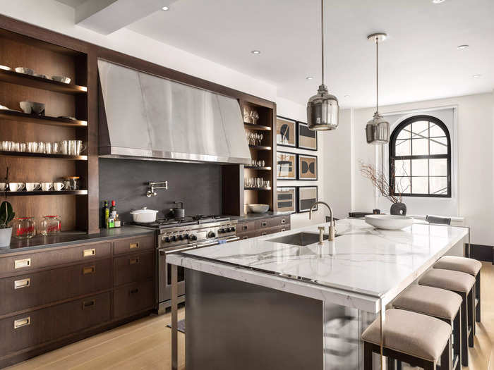 The kitchen also has a Calacatta marble island, dual dishwashers, a six-burner stove, and a wine refrigerator.