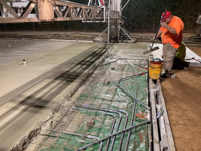 Tubing for plumbing and electricity is placed along the foundation, and then a slab of concrete is placed on top.